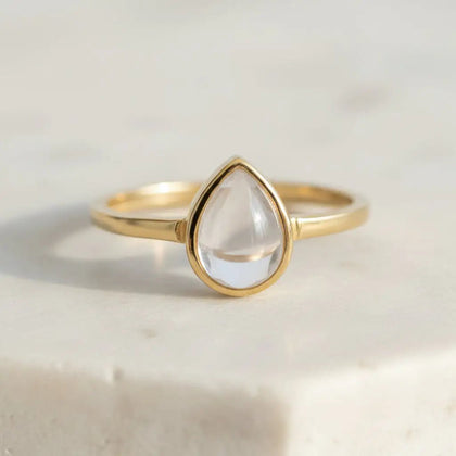 Gold April birthstone ring with clear herkimer quartz teardrop-shaped stone on a light background - quartz ring for gifting