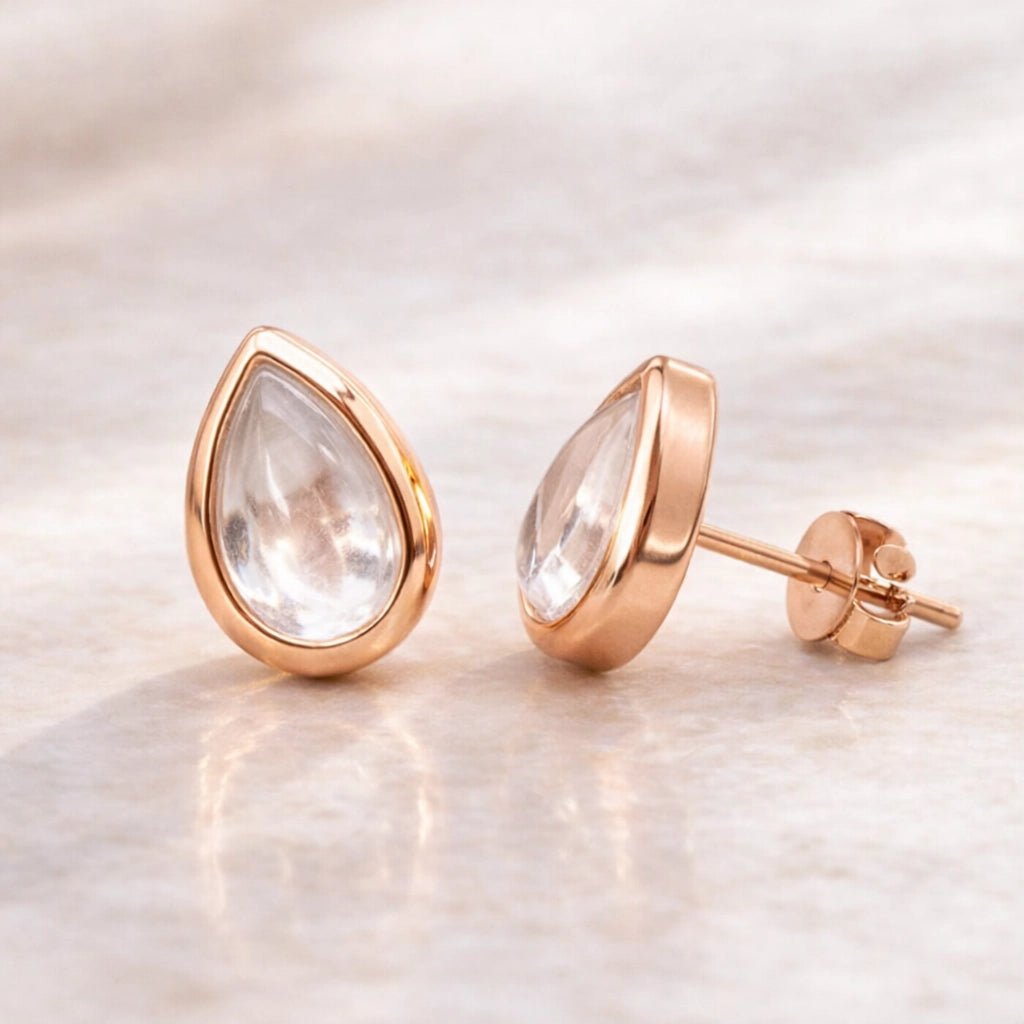 Rose gold teardrop earrings with clear natural herkimer quartz gemstones on a light background