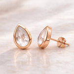 Rose gold teardrop earrings with clear natural herkimer quartz gemstones on a light background