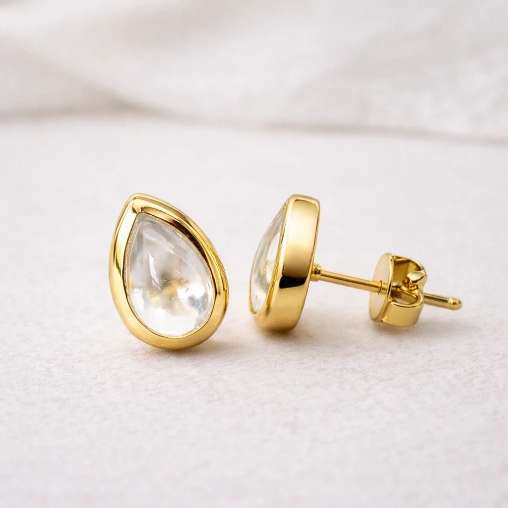 Gold stud earrings with clear herkimer quartz teardrop-shaped stones on a light background