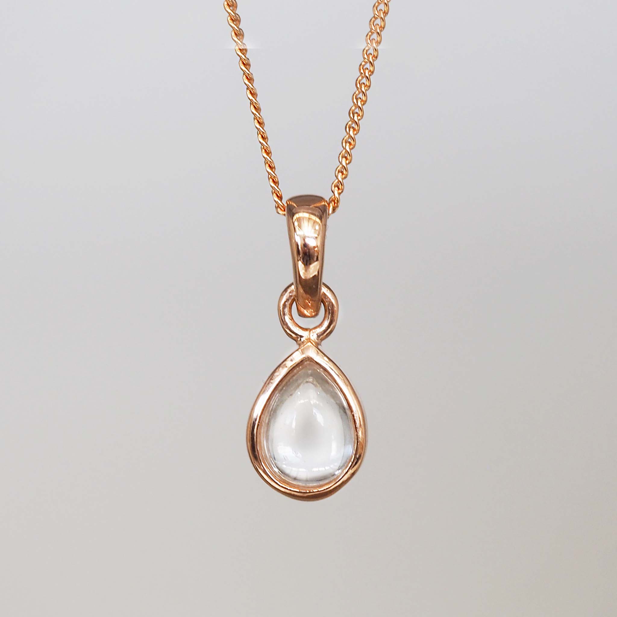 Rose gold teardrop pendant necklace on a light gray background