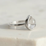 Sterling Silver April Birthstone Ring with a teardrop-shaped natural Clear Quartz gemstone on a light background