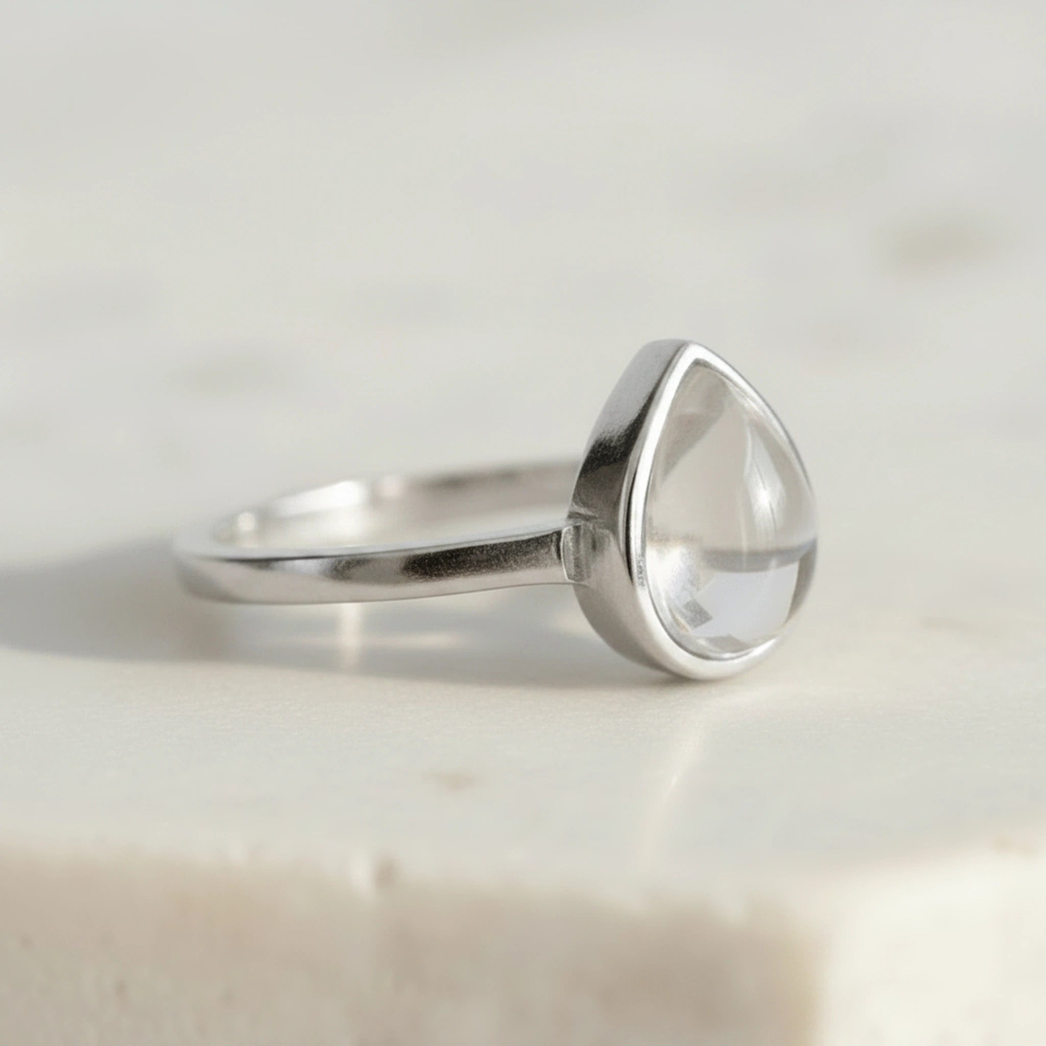 Sterling Silver April Birthstone Ring with a teardrop-shaped natural Clear Quartz gemstone on a light background