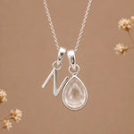 sterling silver initial n april birthstone natural clear quartz pendant necklace against a dark warm beige background