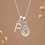 sterling silver initial p april birthstone natural clear quartz pendant necklace against a dark warm beige background