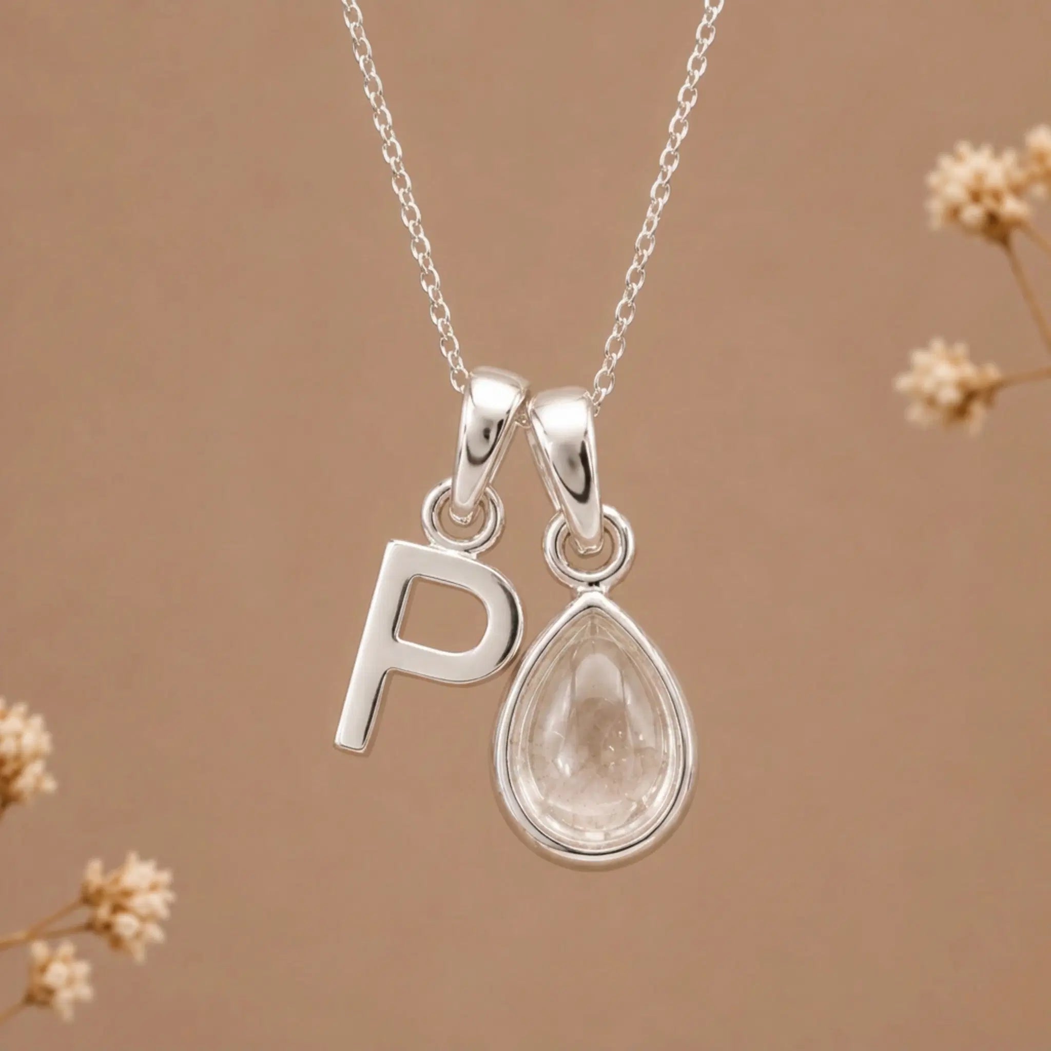 sterling silver initial p april birthstone natural clear quartz pendant necklace against a dark warm beige background