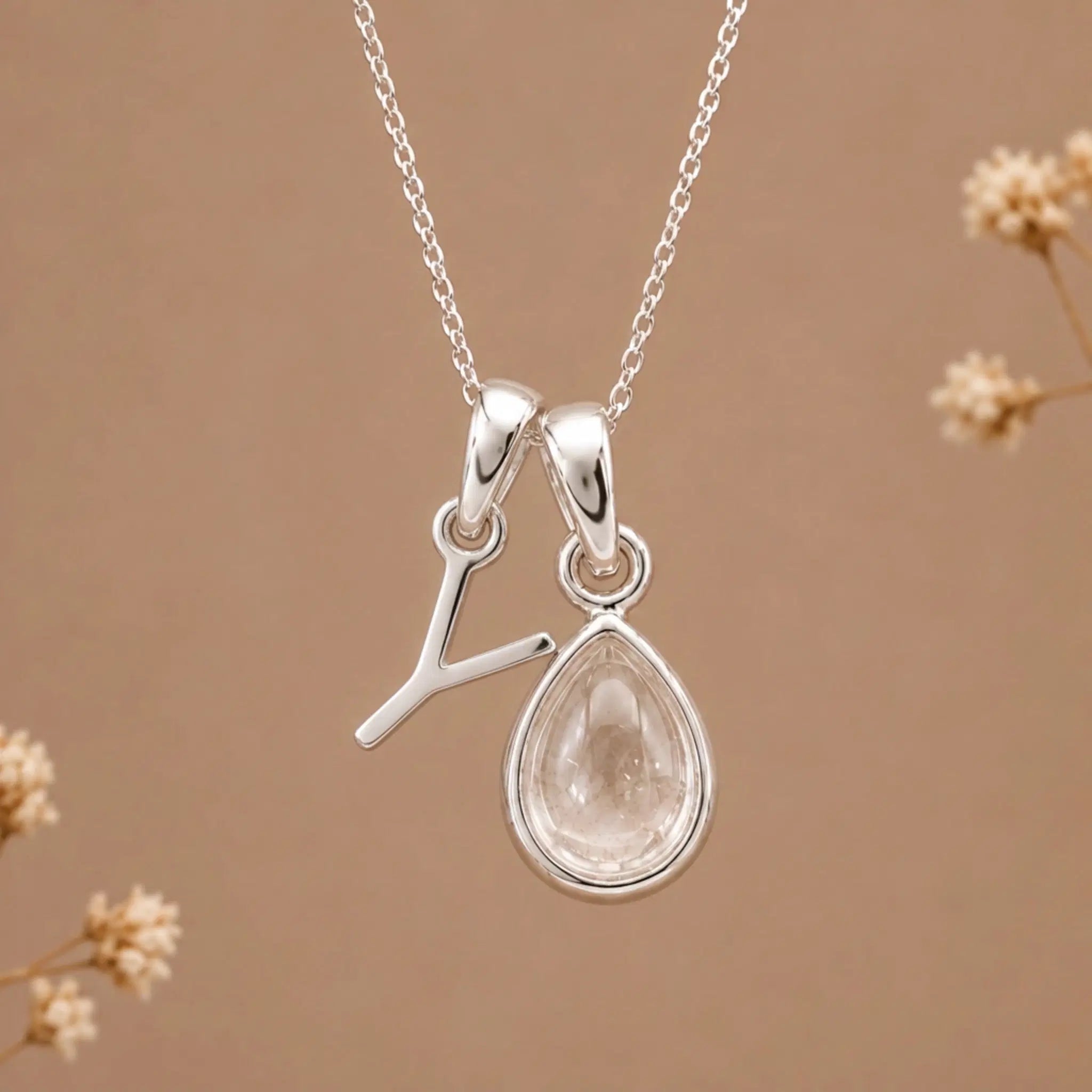sterling silver initial y april birthstone natural clear quartz pendant necklace against a dark warm beige background