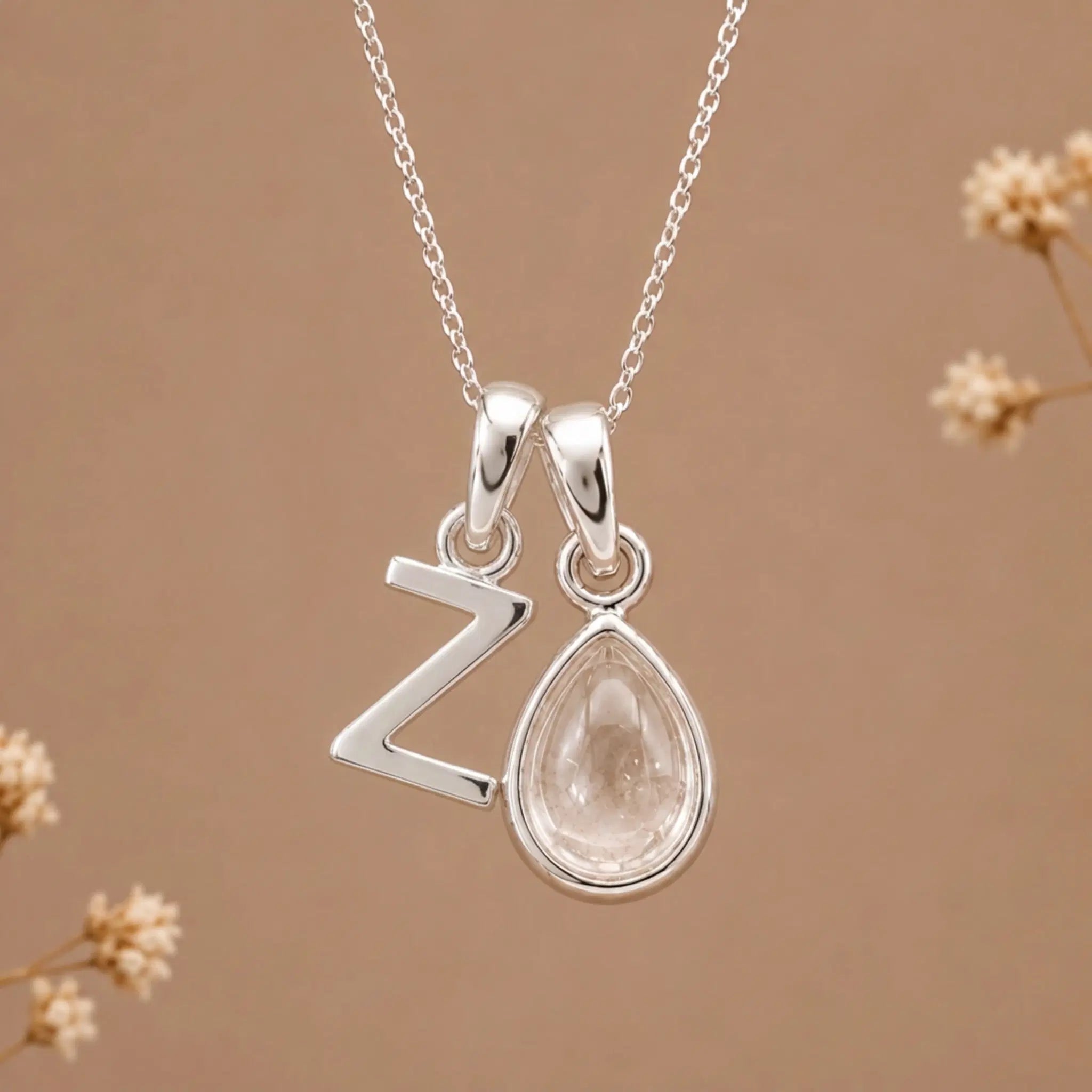 sterling silver initial z april birthstone natural clear quartz pendant necklace against a dark warm beige background