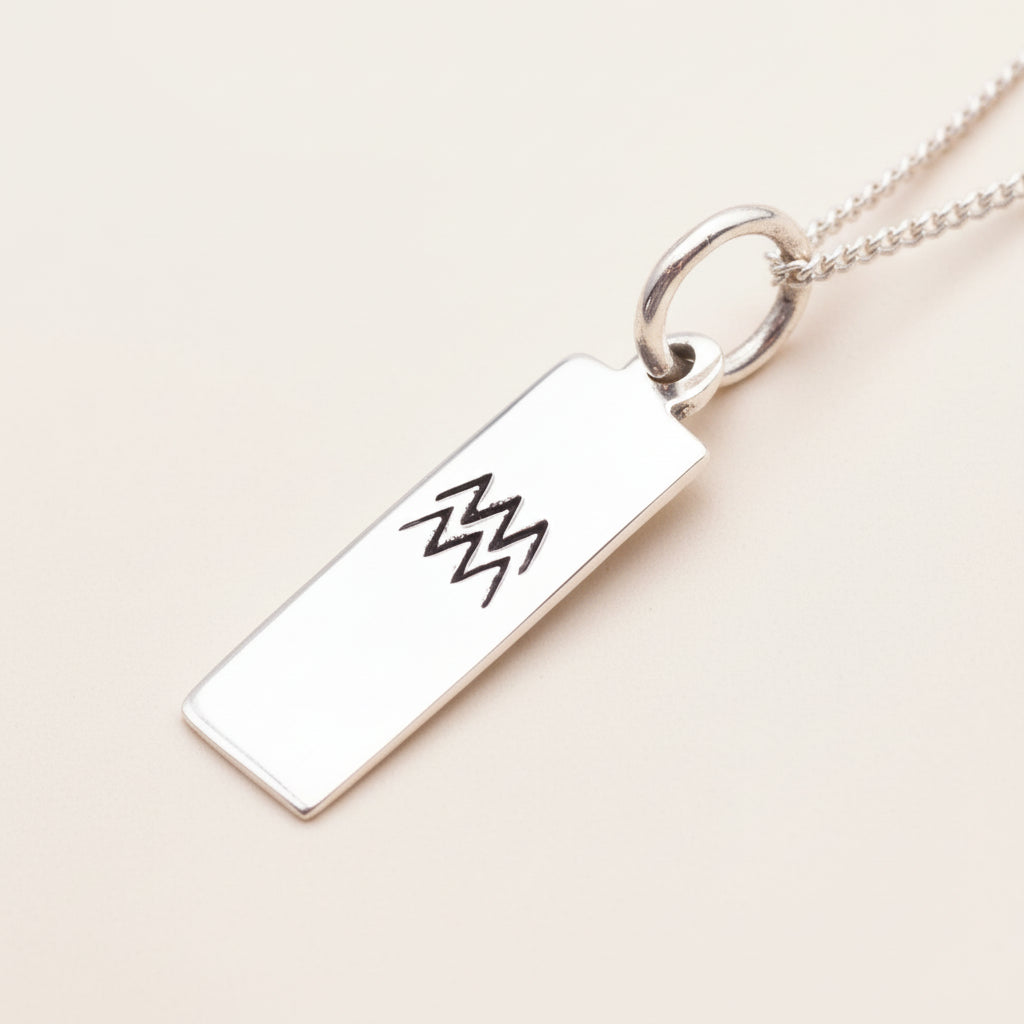 sterling Silver pendant with engraved aquarius zodiac design on a white background