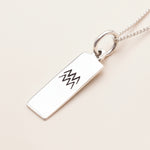 sterling Silver pendant with engraved aquarius zodiac design on a white background
