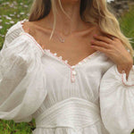 Woman wearing a white dress with intricate details in a natural setting