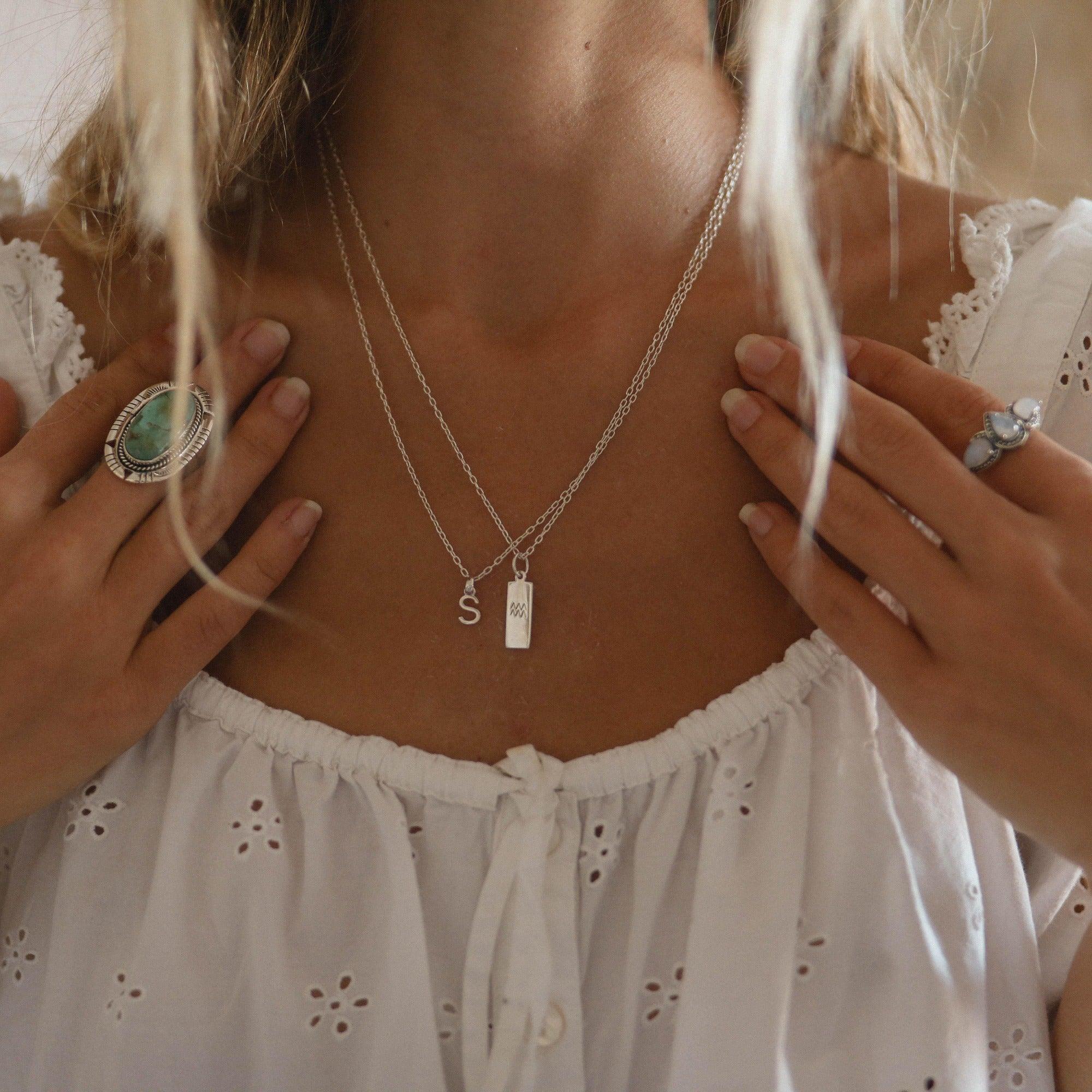 lady with blonde hair wearing sterling silver initial S necklace and silver zodiac necklace