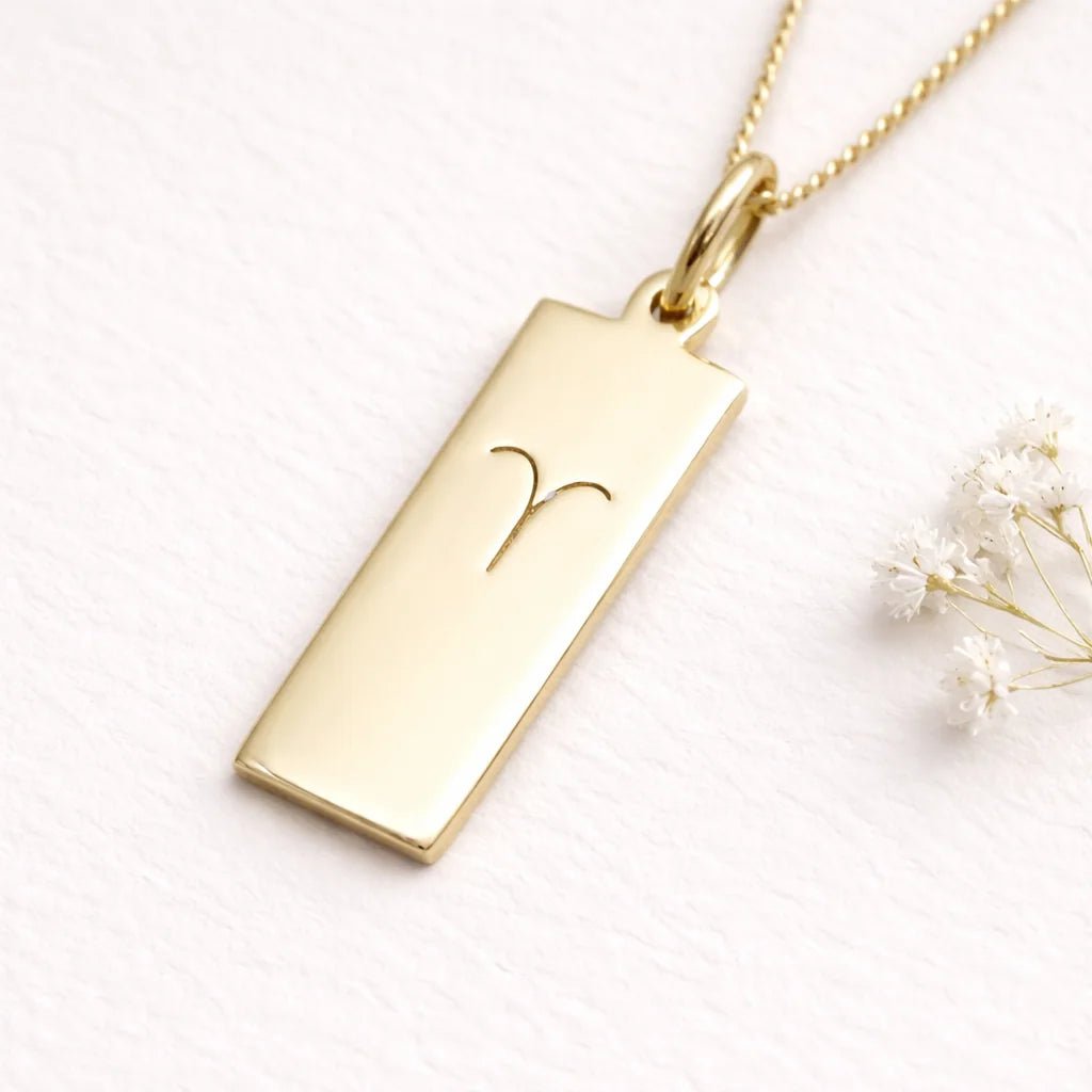gold necklace with a rectangle pendant with aries zodiac symbol