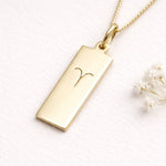 gold necklace with a rectangle pendant with aries zodiac symbol
