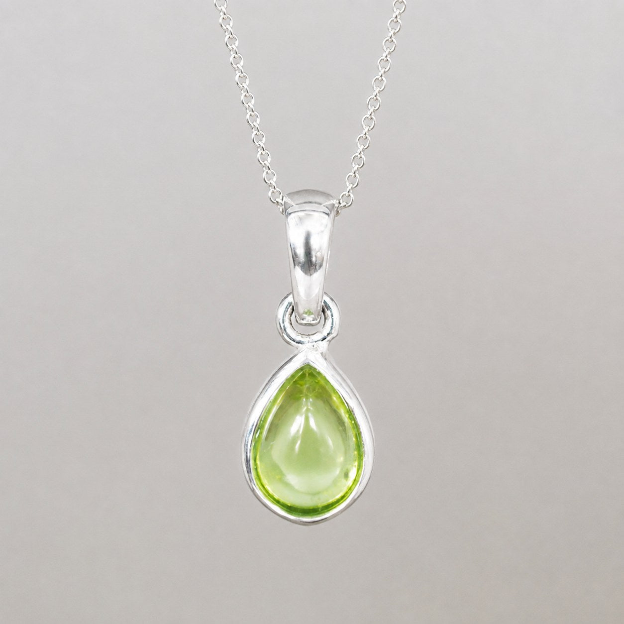 Sterling silver August birthstone necklace with a natural light green peridot teardrop pendant, bezel set on a fine chain.