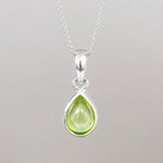 Sterling silver August birthstone necklace with a natural light green peridot teardrop pendant, bezel set on a fine chain.