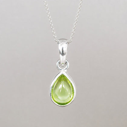Sterling silver August birthstone necklace with a natural light green peridot teardrop pendant, bezel set on a fine chain.