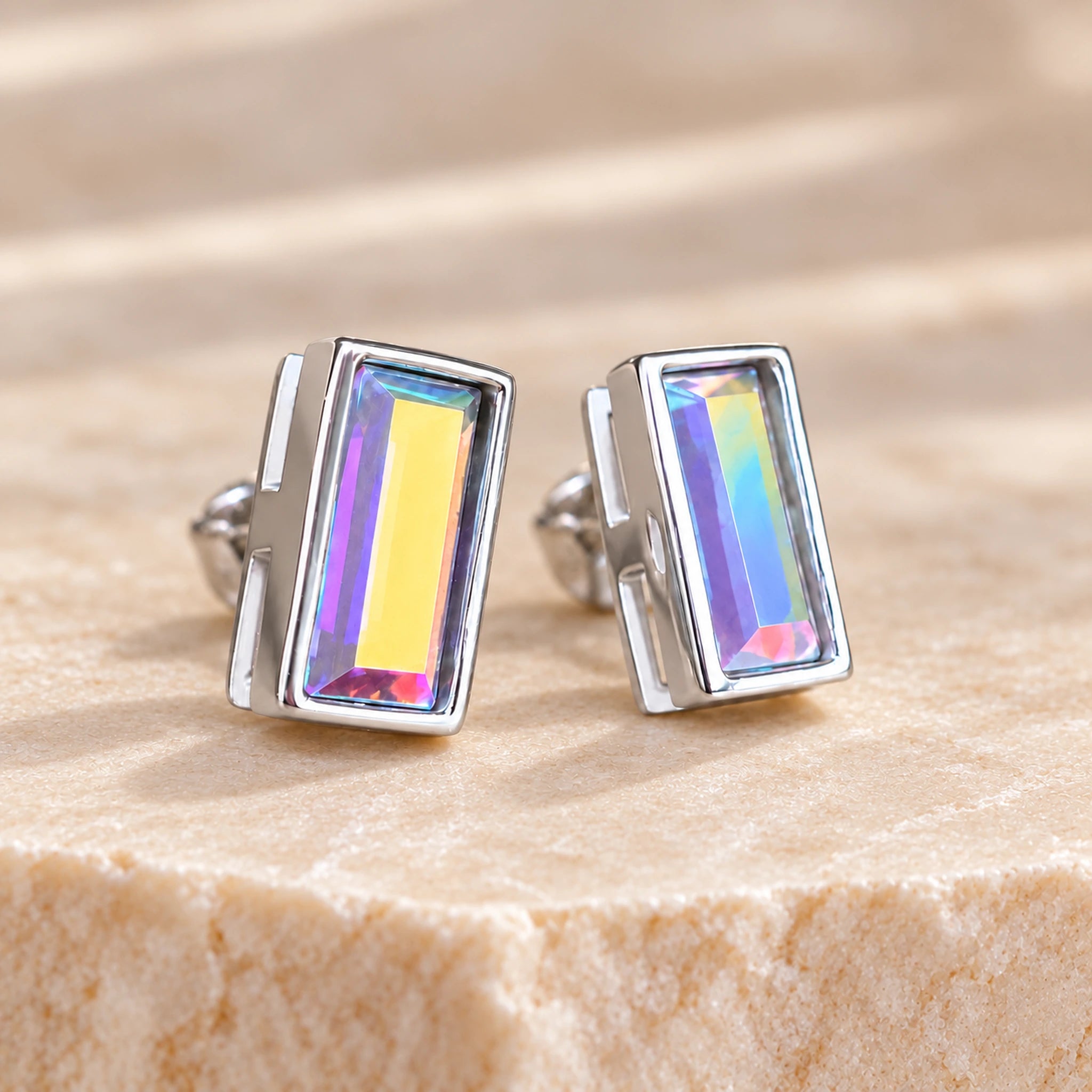 Aurore Boreale crystal baguette stud earrings in polished rhodium silver showing yellow and lilac colour flashes