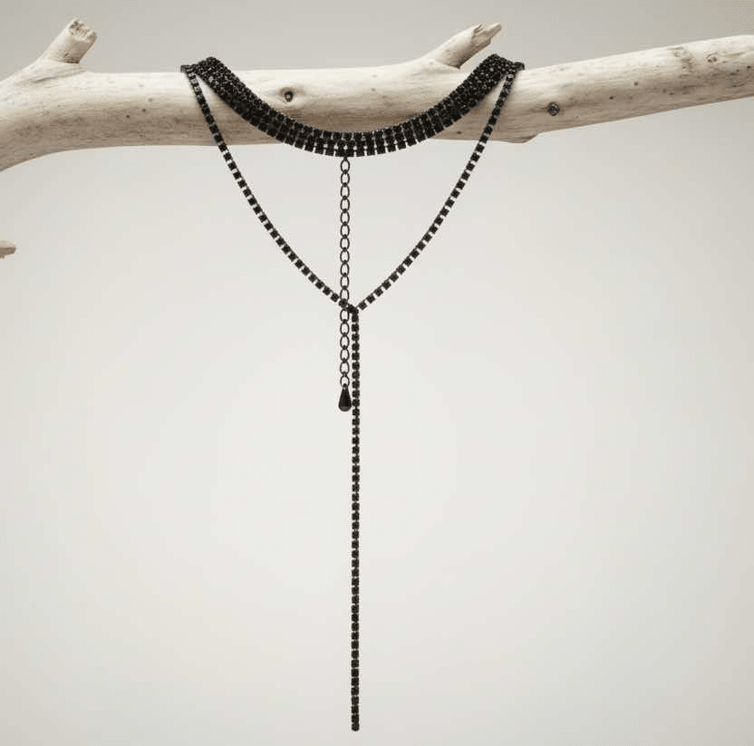 Black beaded necklace on a branch against a light background