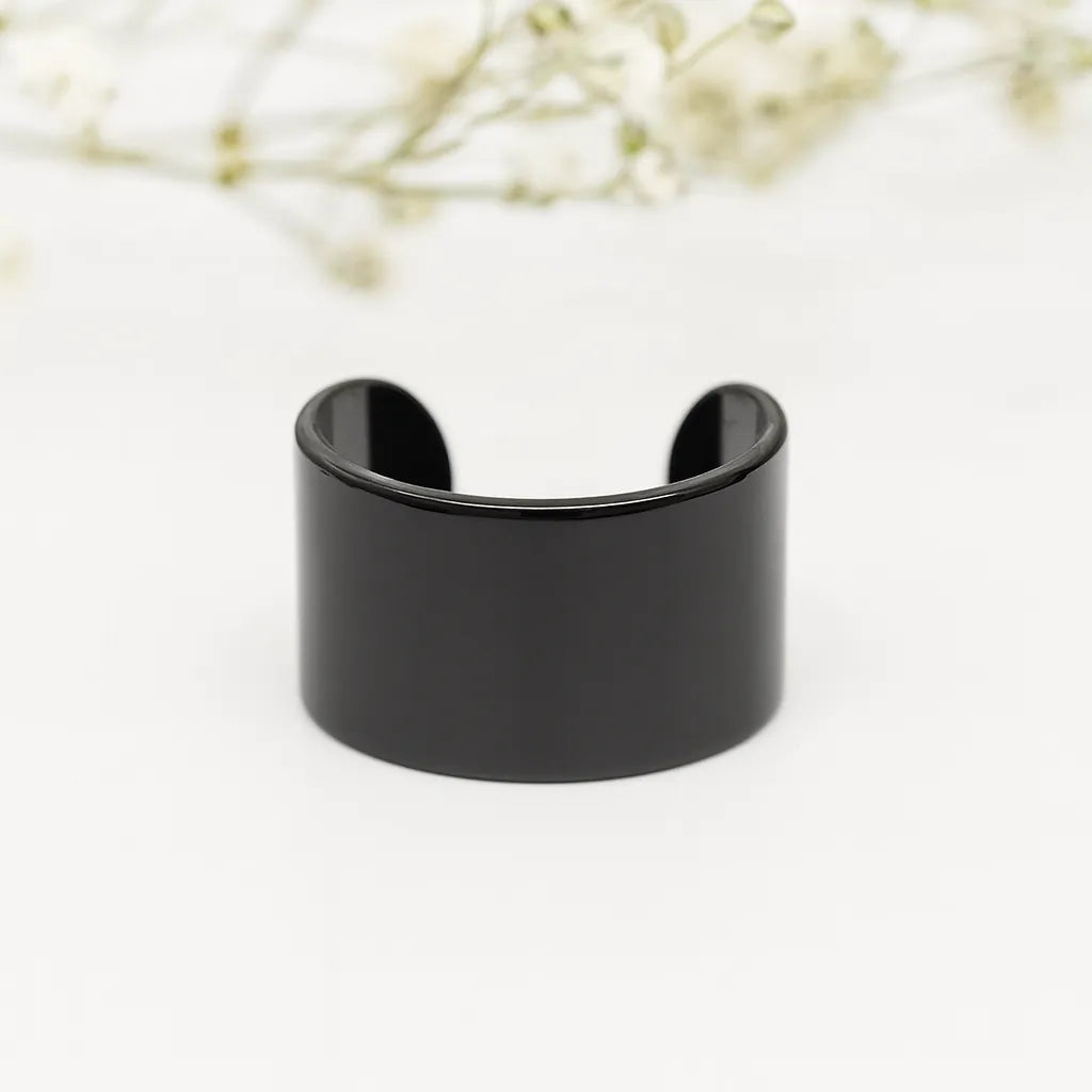 Black ear cuff on a light background with blurred flowers in the background - waterproof jewellery australia