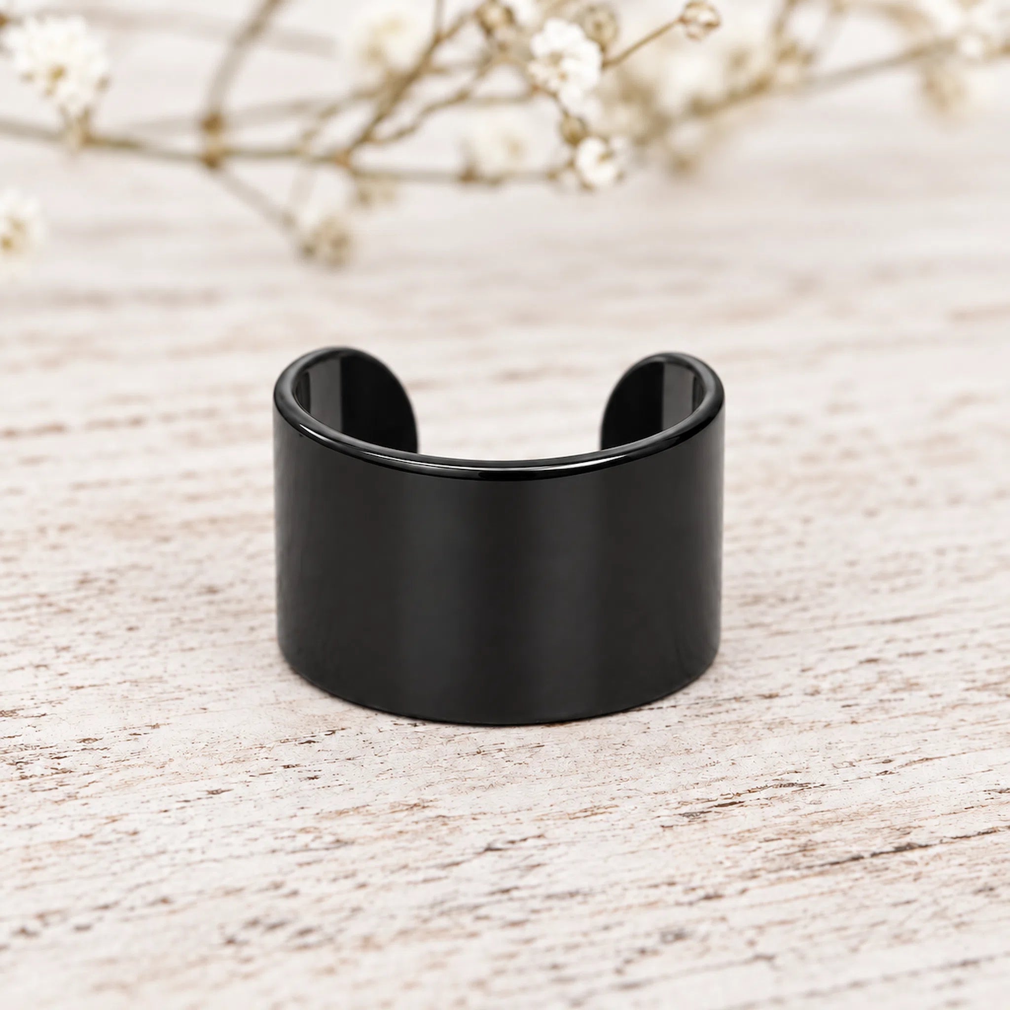 Black ear cuff on a light background with blurred flowers in the background - waterproof jewellery australia