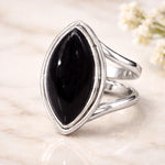 Silver ring with a large black gemstone on a light background