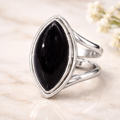 Silver ring with a large black gemstone on a light background