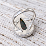 Back view of the bloodstone teardrop ring showing the open silver setting on whitewashed wood