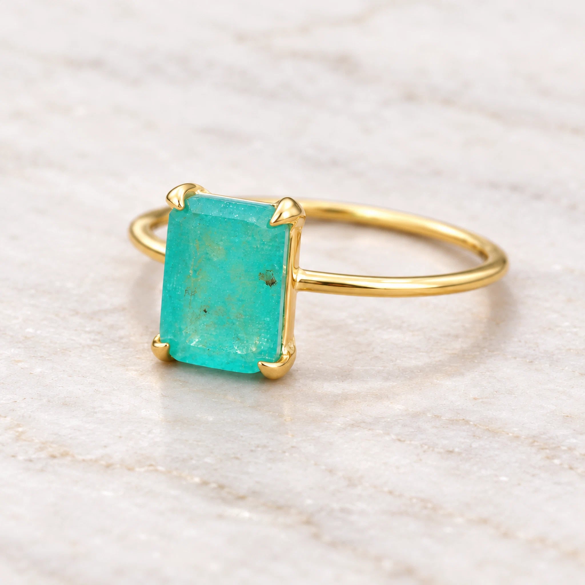 Gold boho ring with a green blue faceted natural tourmaline gemstone on a neutral background