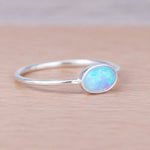 Silver ring with a blue opal stone on a wooden surface