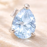 Sterling Silver Pear Shaped stud earring with faceted blue topaz gemstones on a light surface.