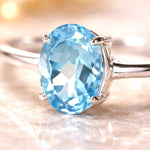 Silver ring with a blue topaz gemstone on a soft focus background