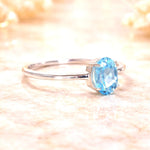 Sterling Silver ring with a oval faceted claw set natural blue topaz gemstone on a soft, blurred background