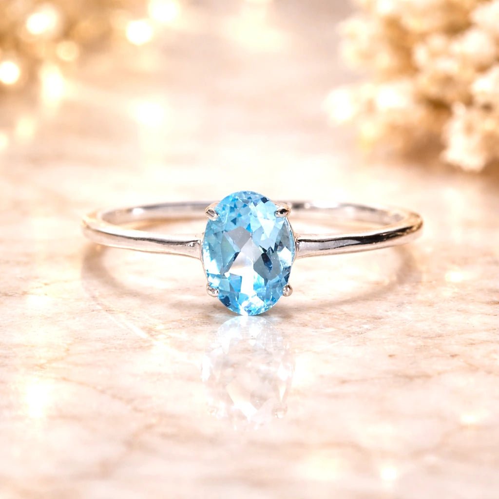 Sterling Silver ring with a oval faceted claw set natural blue topaz gemstone on a soft, blurred background