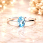 Sterling Silver ring with a oval faceted claw set natural blue topaz gemstone on a soft, blurred background