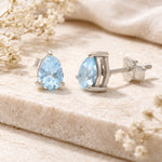 Sterling Silver Pear Shaped stud earrings with faceted blue topaz gemstones on a light surface.