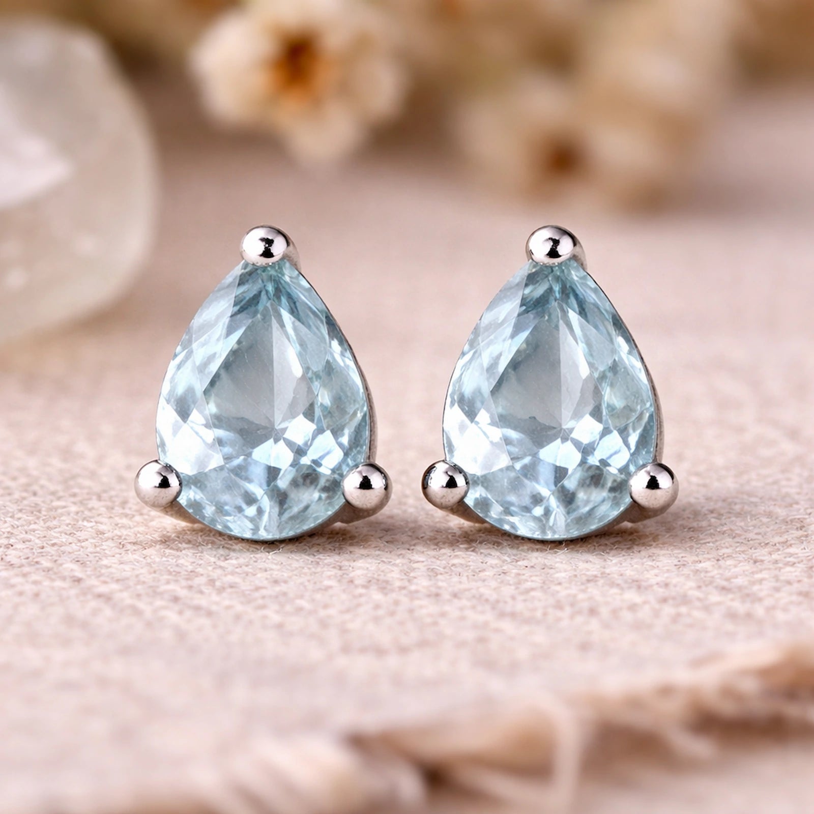 Sterling Silver Pear Shaped stud earrings with faceted blue topaz gemstones on a light surface.