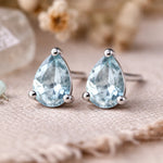 Sterling Silver Pear Shaped stud earrings with faceted blue topaz gemstones on a light surface.