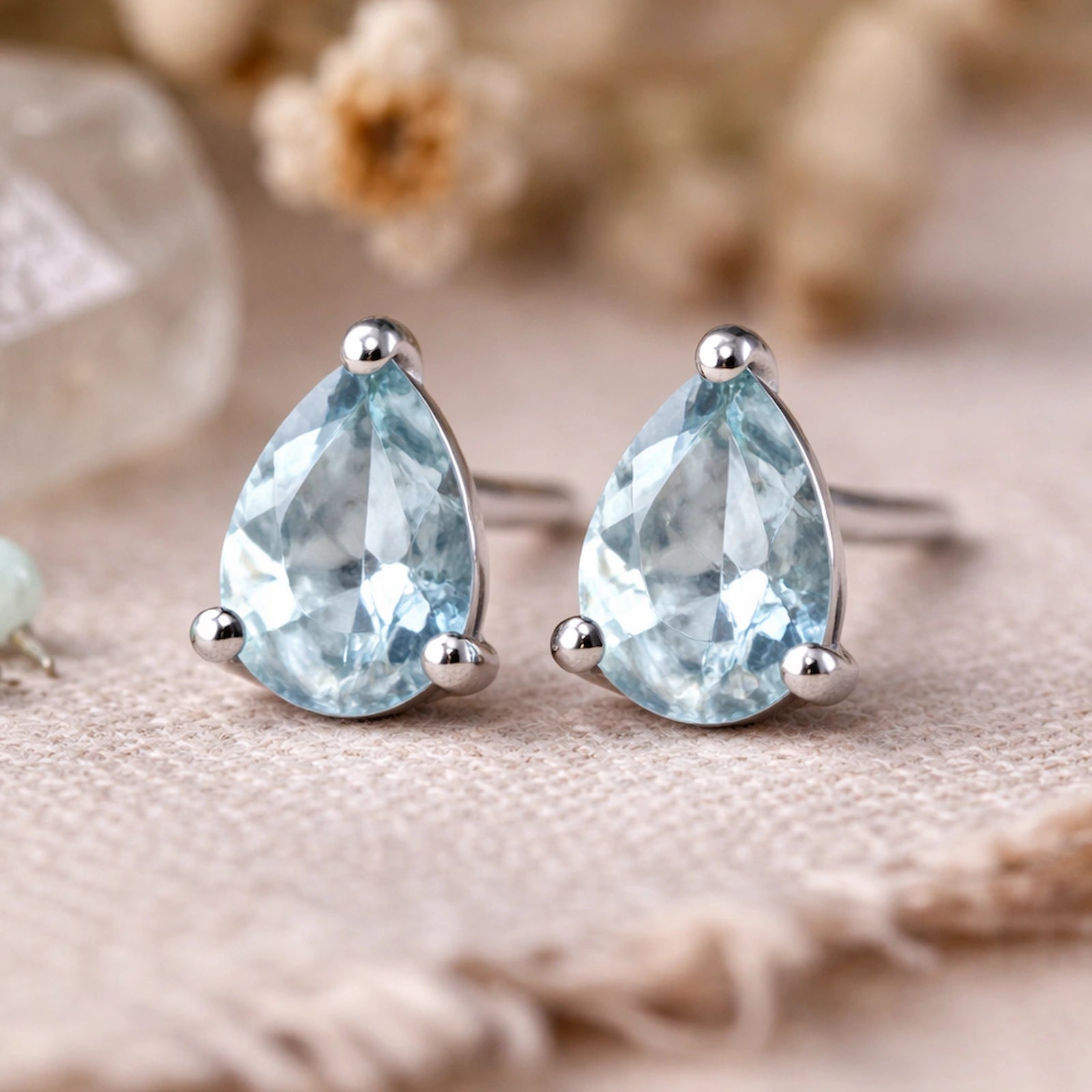 Sterling Silver Pear Shaped stud earrings with faceted blue topaz gemstones on a light surface.