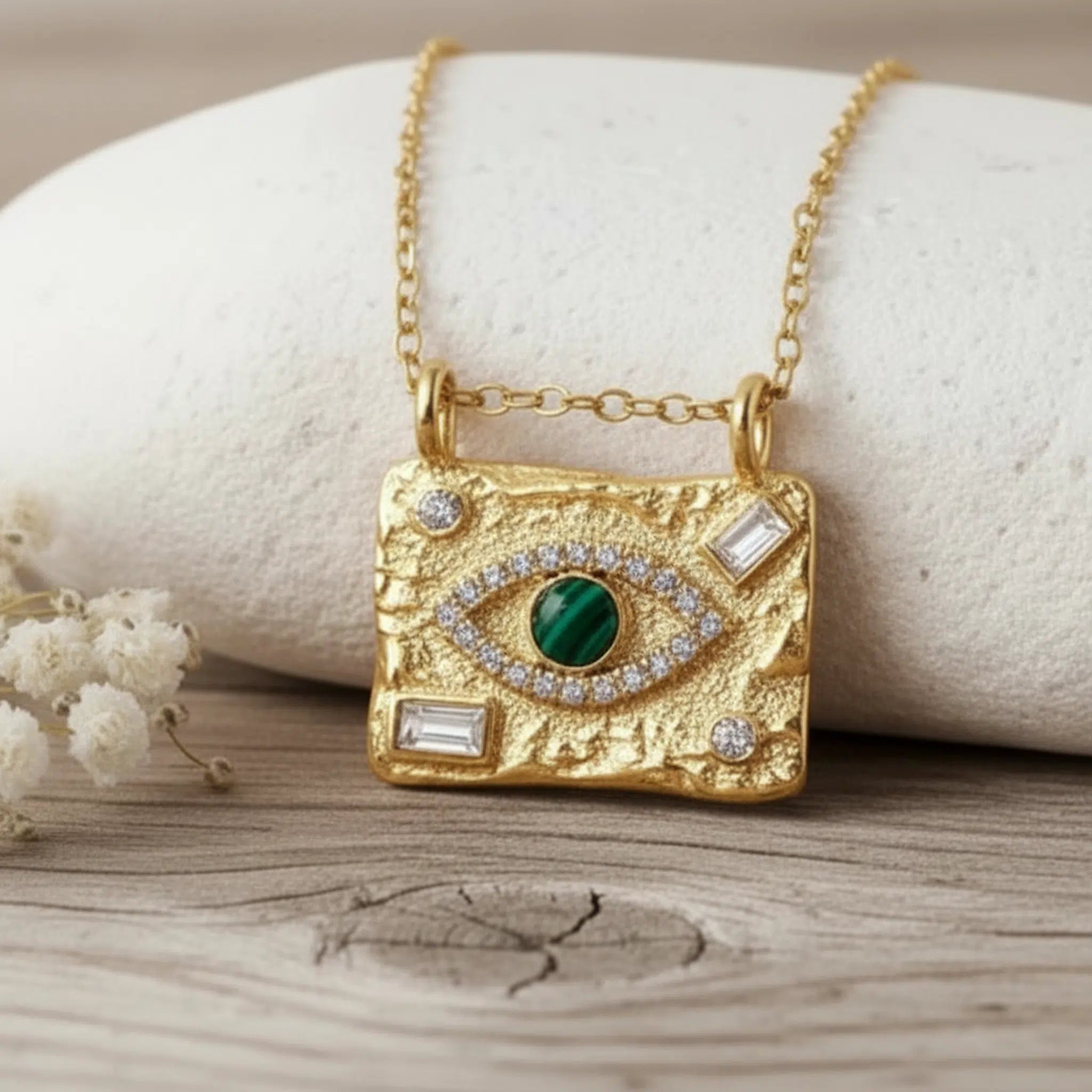 Boho Evil Eye Waterproof Gold Necklace in stainless steel hanging in front of a stone