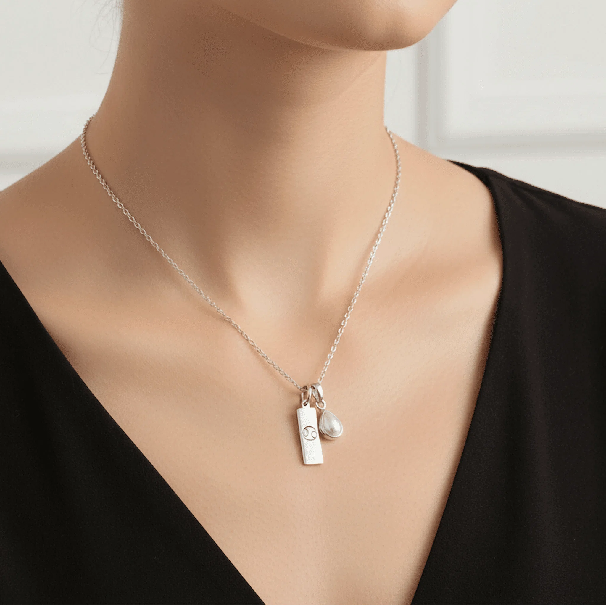 Sterling Silver June Birthstone Necklace with a pear-shaped Mother of Pearl pendant and a cancer zodiac star sign pendant being worn
