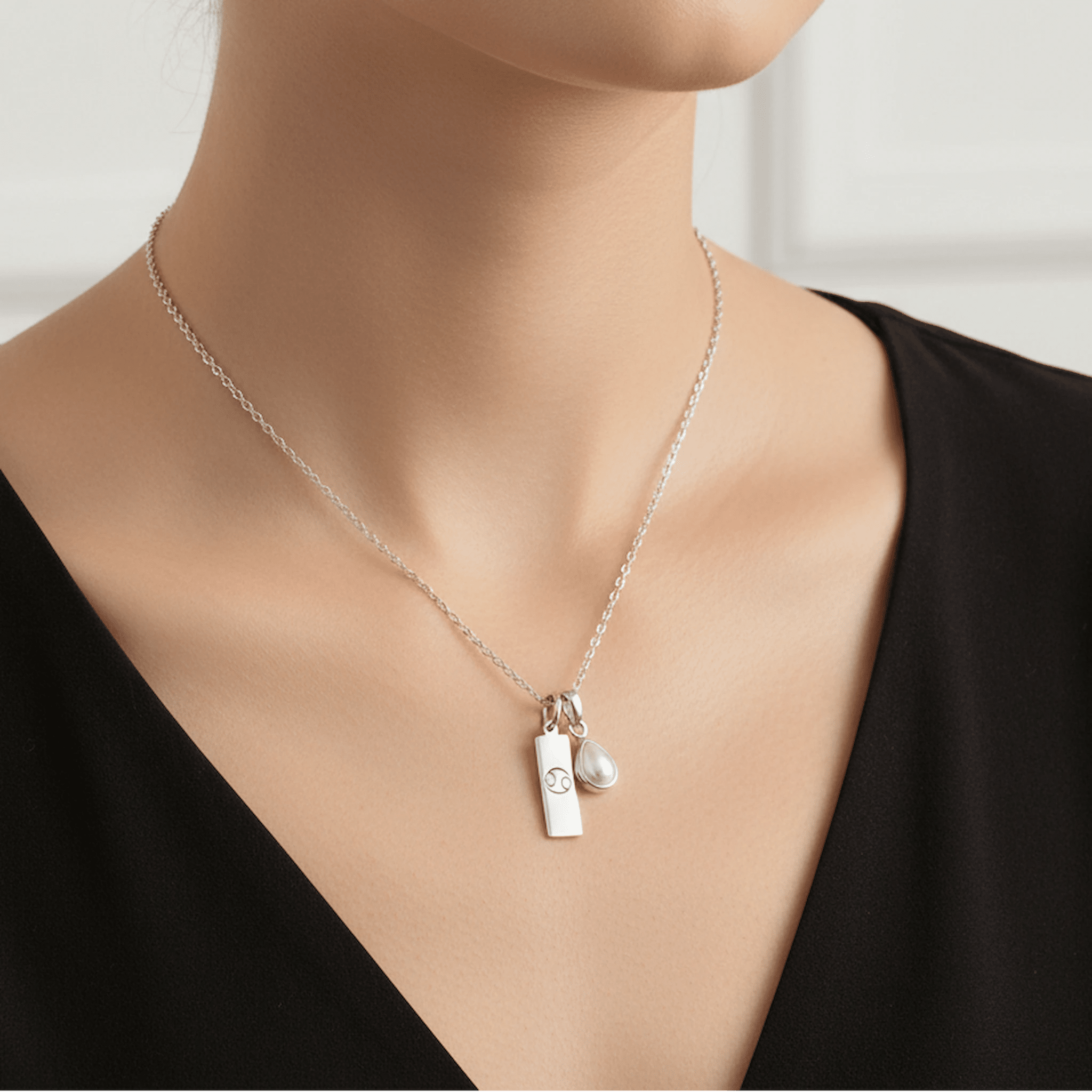 Sterling Silver Necklace with a June Birthstone Pearl pendant and a cancer zodiac star sign pendant being worn