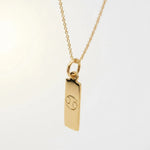 Gold pendant with cancer zodiac symbol on a light background