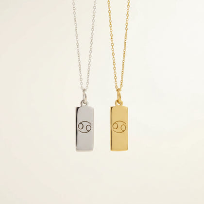 Gold and silver necklaces with cancer zodiac pendants on a beige background
