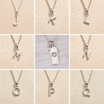 Silver letter pendants from J to Q on a beige background as personalised letter options for the Cancer Zodiac Necklace