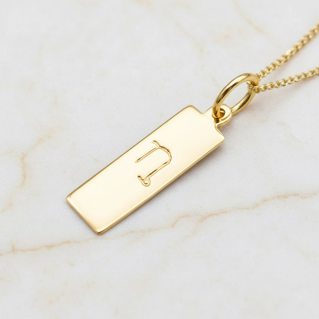 capricorn zodiac necklace in 9k gold plated sterling silver on a white stone surface