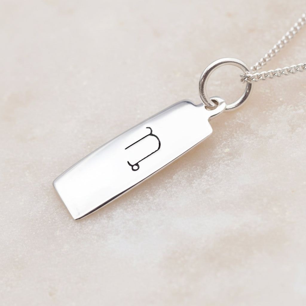 Capricorn zodiac necklace in sterling silver on a white surface 