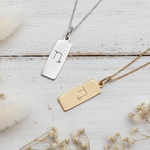 Capricorn zodiac necklaces in silver and gold on a wooden surface 