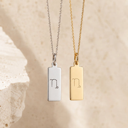 sterling silver and gold fine chain necklaces with a rectangle pendants engraved with the capricorn zodiac line glyph symbol hangin