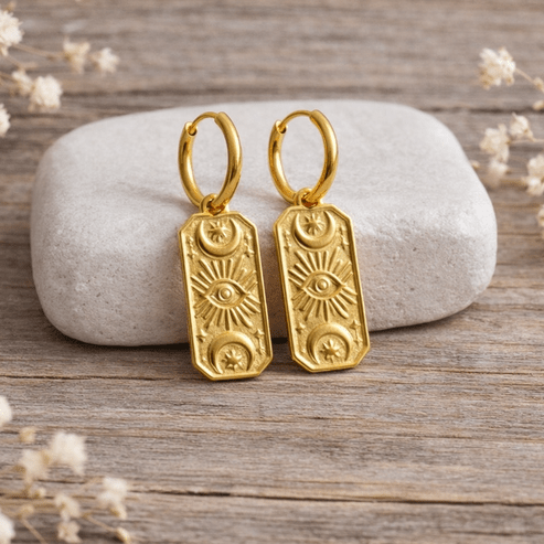 Gold earrings on a white stone with a soft background